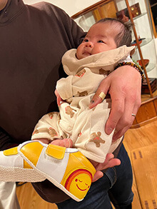 ニコニコちゃんモチーフのシューズを履く赤ちゃん