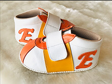 白とオレンジの本革ベビースニーカーにイニシャル「E」を入れた例